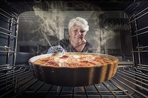 woman putting apple pie in oven