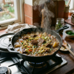 Cast iron skillet with simmering braised beef with cabbage containing beef chunks, potatoes, carrots, and greens